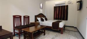 a bedroom with a bed and a table and chairs at Rmc travellers inn in Chennai