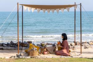 een vrouw op het strand die naar de oceaan kijkt bij Devasom Hua Hin Resort in Cha Am