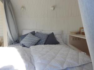 a bed in a room with pillows on it at Tiny House De Boet, in Natuurgebied en vlakbij het Strand in Callantsoog