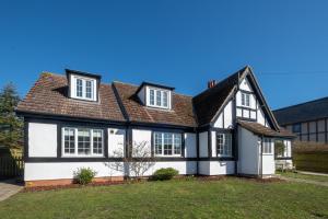 a white house with a black roof at 6 Lakeside Avenue in Thorpeness