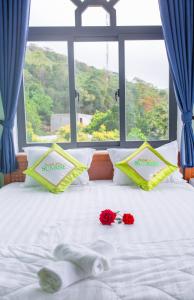 a bed with two roses on it with a window at SUNRISE HOTEL in Con Dao