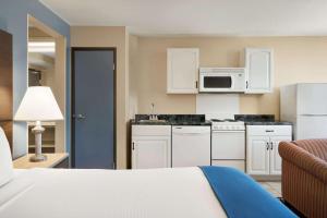 a kitchen with white cabinets and a microwave at Baymont by Wyndham Ft. Leonard/Saint Robert in Saint Robert