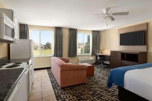 a hotel room with a bedroom with a bed and a desk at Baymont by Wyndham Ft. Leonard/Saint Robert in Saint Robert