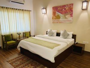 a bedroom with a large bed and two chairs at Sanskriti Vedic Retreat in Rishīkesh