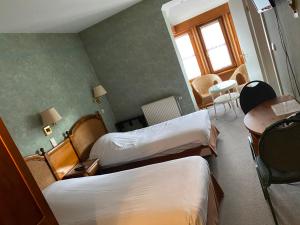 ein Hotelzimmer mit zwei Betten und einem Tisch in der Unterkunft Hotel du Roy in Bouillon