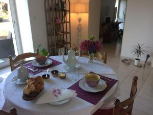 una mesa con un mantel blanco con tazas y sets de té en Chambre d'hôtes La Haie en Roz-Landrieux