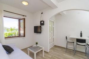 a white room with a bed and a table and a window at Apartments Vitorin in Sobra
