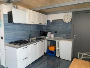 eine Küche mit weißen Schränken, einer Spüle und einer Uhr in der Unterkunft Agenzia Isotur PESCATORI in Ponza