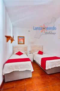 a bedroom with two beds with red and white sheets at Vivienda Vacacional Los Molinos 6205 in Costa Teguise