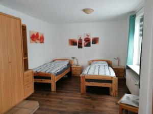 two beds in a room with wooden floors at Ellen`s Pension in Dobbrun