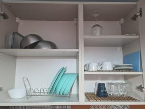 - une étagère avec de la vaisselle et des ustensiles dans la cuisine dans l'établissement Apartment Aviatiei 61, à Bucarest