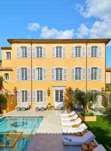 un grand bâtiment jaune avec des chaises longues et une piscine dans l'établissement Airelles Pan Dei Palais, à Saint-Tropez