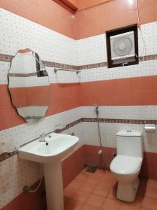 W łazience znajduje się umywalka, toaleta i lustro. w obiekcie Sunshine Hotel w mieście Trikunamalaja