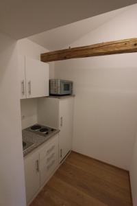 een keuken met witte kasten en een magnetron bij Appartements Bad Birnbach in Bad Birnbach