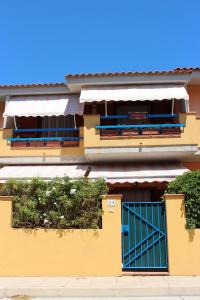 a yellow building with blue doors and a fence at Residenza Mediterranea in Villasimius