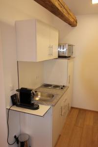 małą kuchnię z białymi szafkami i kuchenką mikrofalową w obiekcie Appartements Bad Birnbach w mieście Bad Birnbach