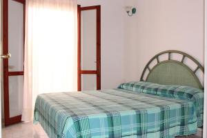 a bedroom with a bed with a plaid blanket on it at Residenza Mediterranea in Villasimius