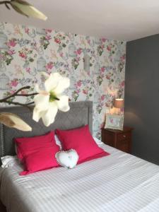 a bedroom with a bed with pink pillows and flowers at Auprès du château in Brézé