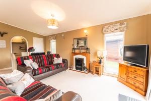 a living room with a couch and a television at Hunters Lodge With Hot Tub in Malton