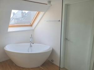 a white bath tub in a bathroom with a window at Spacious Loft in the Historical Centre in Ghent