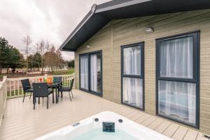 a large deck with a tub and a table and chairs at Honeysuckle Lodge with Hot Tub in York