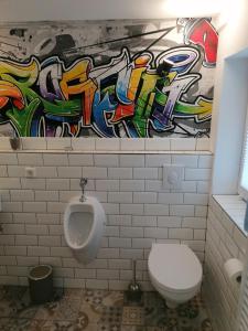 La salle de bains est pourvue de toilettes et d'un mur orné de graffitis. dans l'établissement Tina´s Fewo, à Hohendodeleben