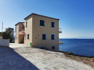 a building on the side of a body of water at Ithaca in Perdika
