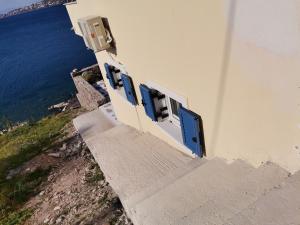 a building with blue doors and stairs next to the ocean at Ithaca in Perdika