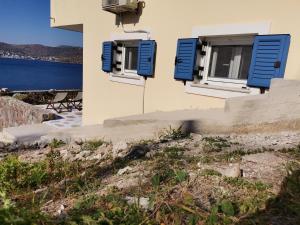 a house with blue shutters and a view of the water at Ithaca in Perdika