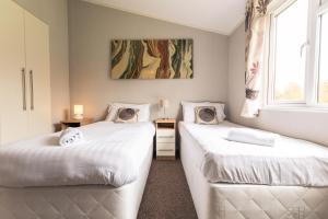 two beds in a room with two windows at Kingfisher Lodge with Hot Tub in Malton +16 photos