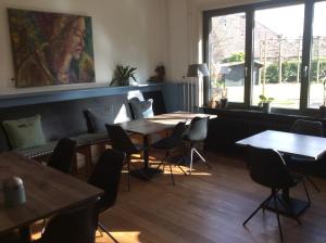 un restaurante con mesas y sillas y una gran ventana en BergOpwaerts, en Sint Odiliënberg