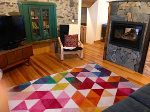 sala de estar con alfombra colorida y chimenea en Casa do Gato, en Góis