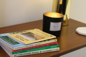 une pile de livres assis sur une table avec une tasse dans l'établissement Boutique Stylish Self Contained Studio Shropshire, à Pattingham