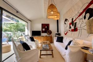 a living room with white furniture and a large window at Le Bastidon de PAMPELONNE in Saint-Tropez