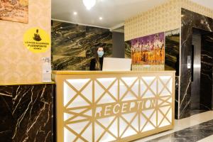 a woman wearing a mask stands behind a reception desk in a lobby at Hotel Yakut in Van
