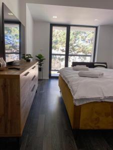 a bedroom with a bed and a dresser with windows at 365 apartmány LINEA in Piešťany +72 photos