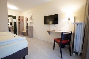 um quarto de hotel com uma cama, uma secretária e uma cadeira em Montana Landhotel Gummersbach-Nord em Marienheide