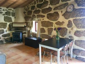 uma sala de jantar com uma mesa e uma parede de pedra em Quinta do Sobral de São Geraldo em São Geraldo