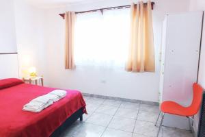 a bedroom with a red bed and a window at Newen in El Calafate +14 photos
