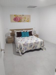 Dormitorio blanco con cama con almohadas azules en Sermican, en Telde