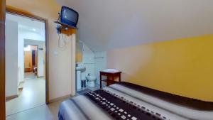 1 dormitorio con 1 cama y TV en la pared en Guest House Estrela, en Oporto