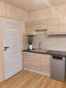 a kitchen with white cabinets and a sink and a door at Domek nad stawem in Robakowo