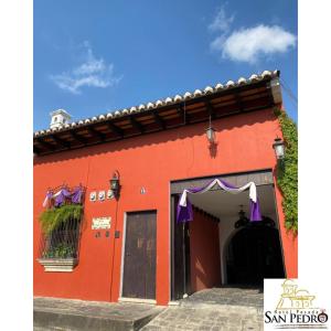 a red building with a black door and a blue sky at Hotel Posada San Pedro in Antigua Guatemala