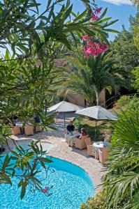 a pool at a resort with people sitting in chairs and umbrellas at La Colline de Vence in Vence