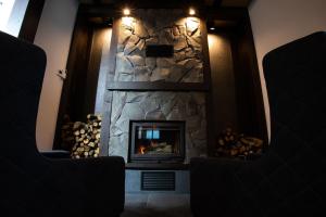 a stone fireplace in a room with two chairs at Apart-hotel Vershina in Yaremche