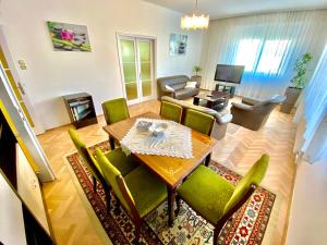 a living room with a table and green chairs at Roselio Garden in Hévíz