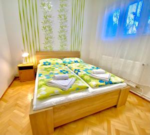 a bedroom with a bed with yellow and blue sheets at Roselio Garden in Hévíz