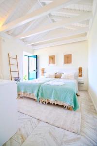 1 dormitorio blanco con 1 cama grande con sábanas verdes en FISH HOUSE 1, en Prainha de Cima