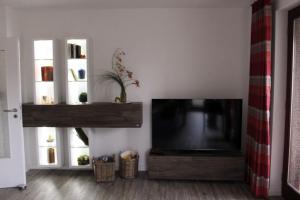 ein Wohnzimmer mit einem Flachbild-TV und 2 Fenstern in der Unterkunft Quartier am Golfplatz in Bad Harzburg