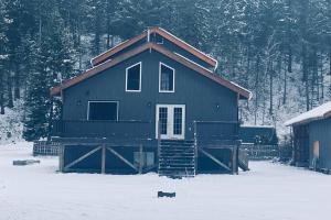 ein Haus im Schnee mit einer Katze davor in der Unterkunft Gudjonson Getaway - 2 bed 2 bath Cabin in Golden